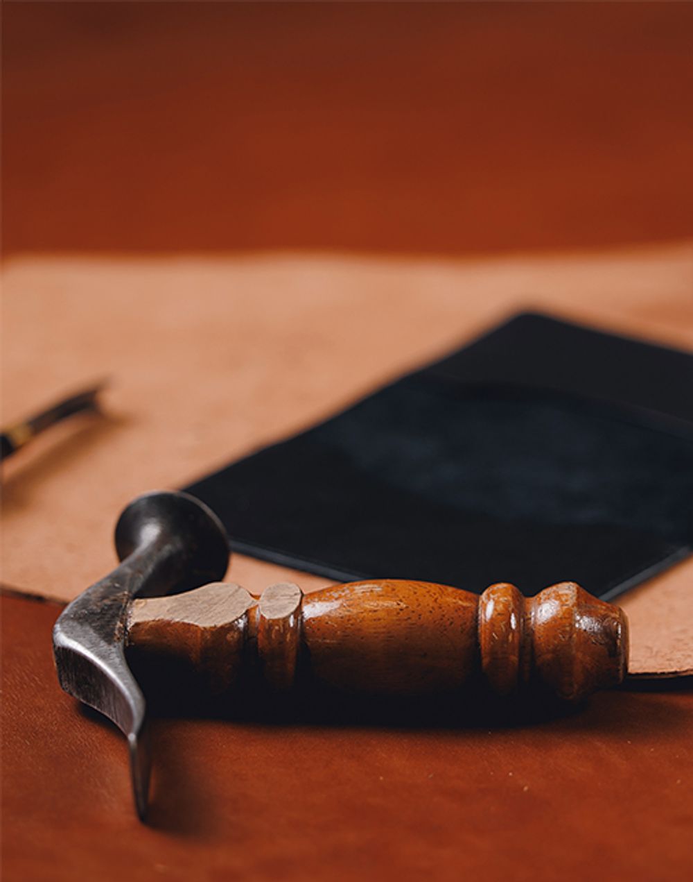Shoe hammer with calf leather in the background.