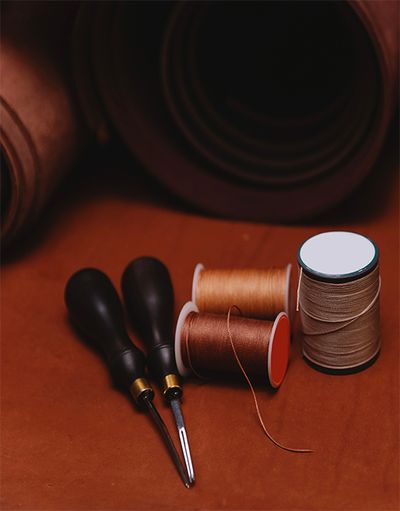 A pair of scissors with shoe cotton and rolls of calf leather.