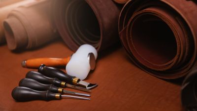 A range of Jasperosso shoemaker tools with rolls of calf leather.